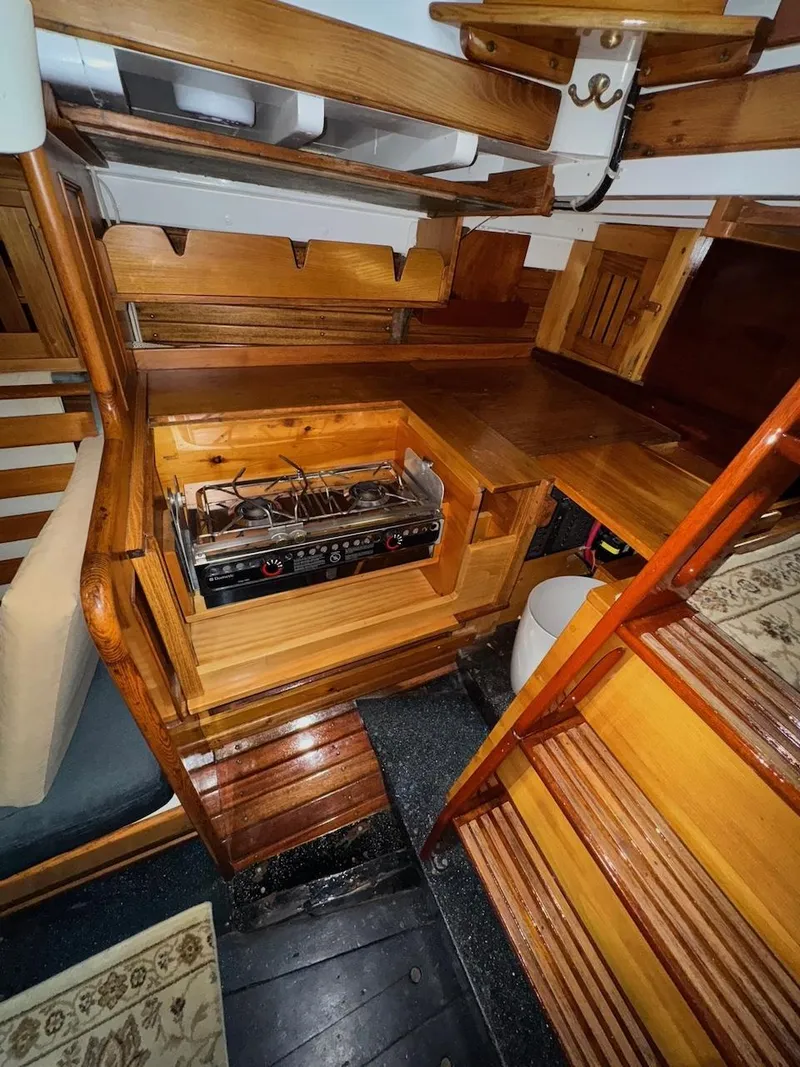 Slide: The Image of Interior of 1955 Concordia 39 Yawl, featuring wooden cabinetry and a compact stove. - 30