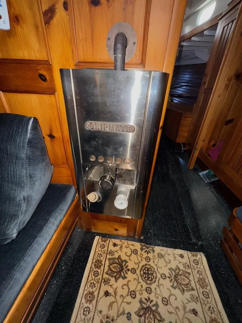 Slide: The Image of Vintage heater inside a 1955 Concordia 39 Yawl, with wooden interior and patterned rug. - 31
