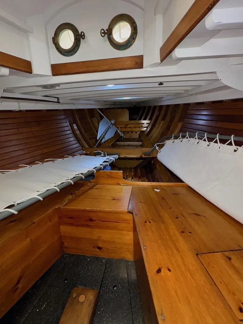 Slide: The Image of Interior of 1955 Concordia 39 Yawl, featuring wooden benches and portholes. - 39