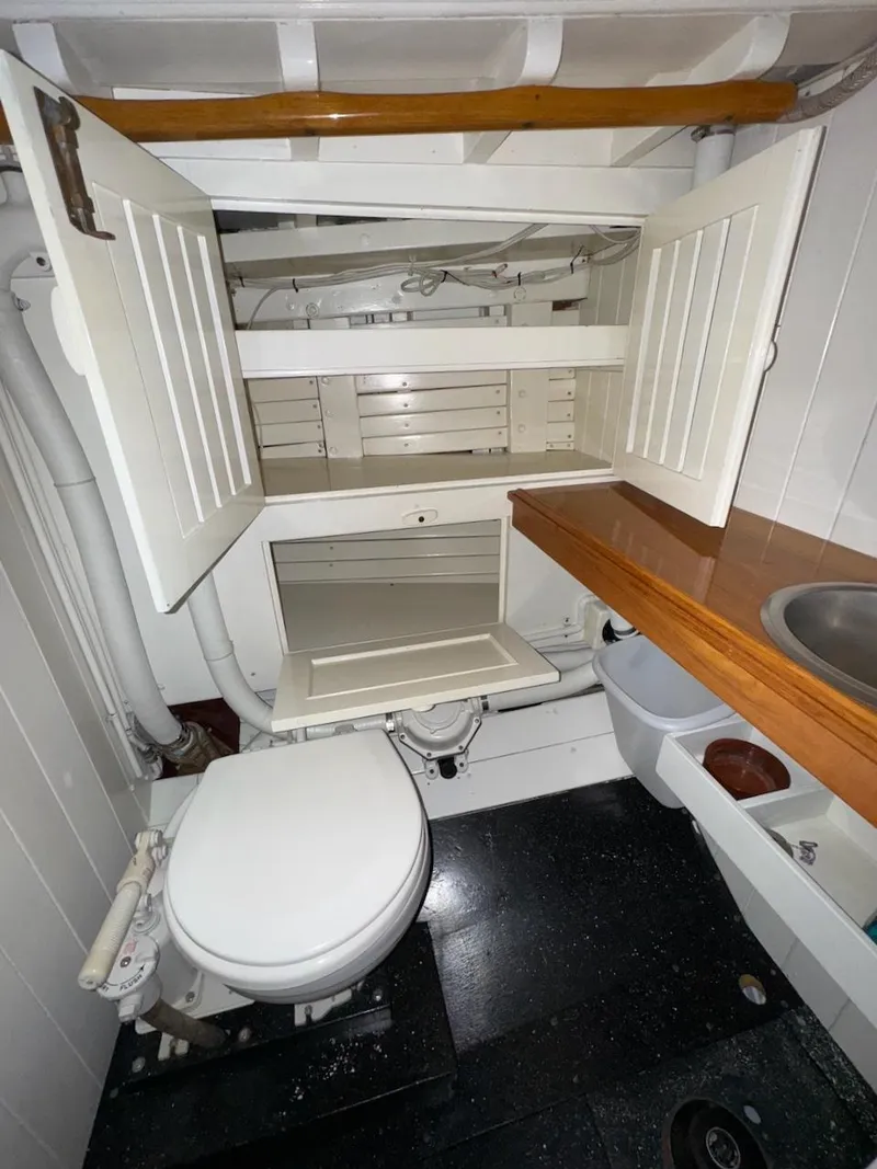 Slide: The Image of Interior of 1955 Concordia 39 Yawl bathroom with toilet, sink, and storage cabinets. - 41