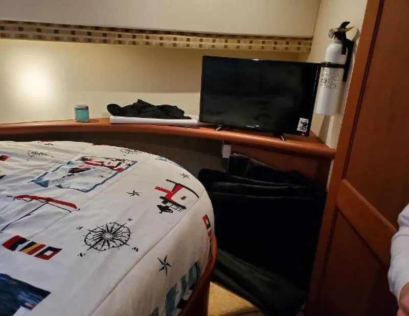 Slide: The Image of 2005 Silverton 34 Convertible cabin interior with nautical-themed bedding and a small TV. - 10