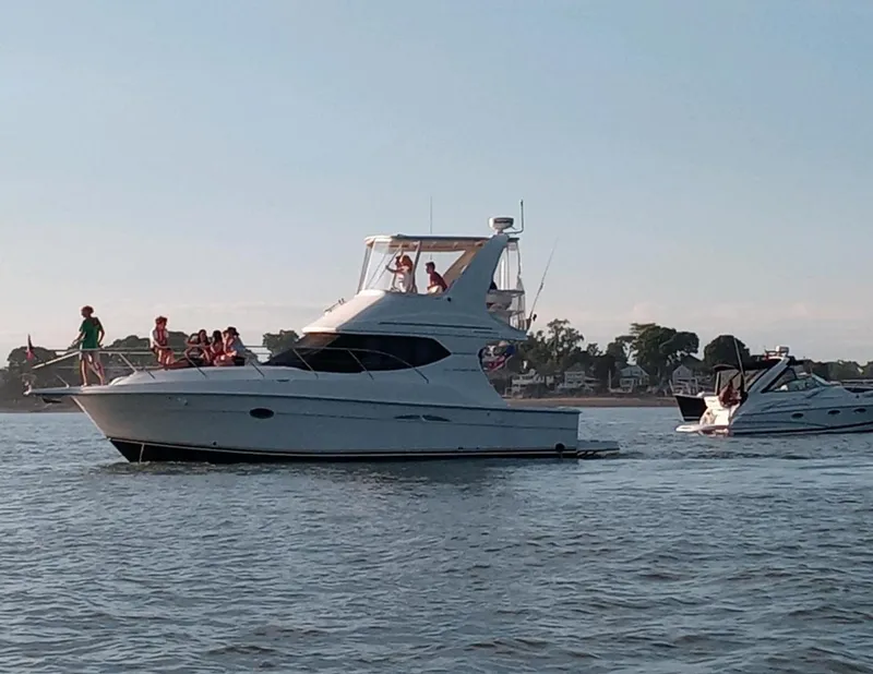 Slide: The Image of 2005 Silverton 34 Convertible yacht cruising on a calm waterway with passengers onboard. - 12