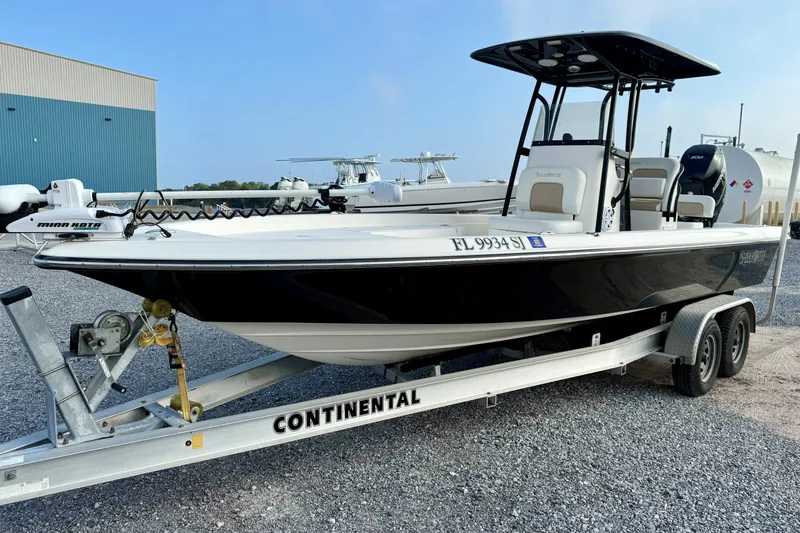 Slide: The Image of 2016 ShearWater 25LTZ boat on Continental trailer, parked on gravel near a blue building. - 0