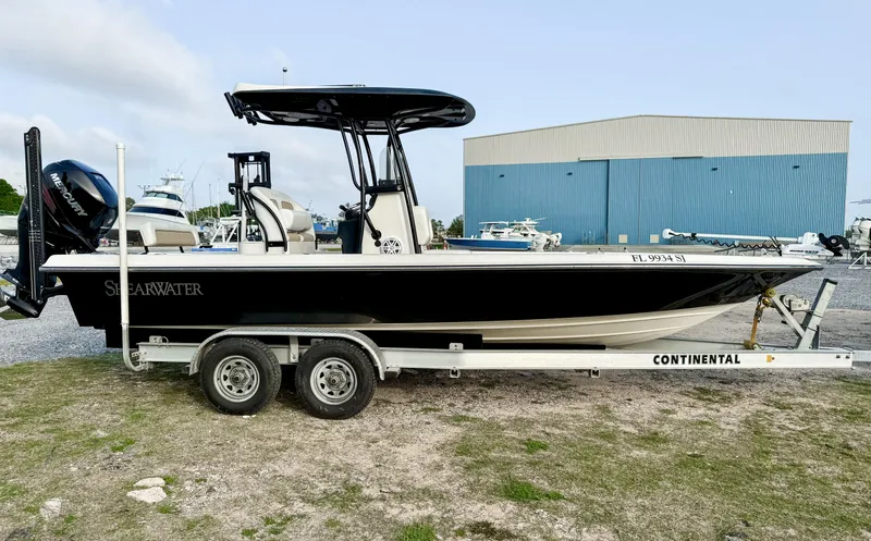 Slide: The Image of 2016 ShearWater 25LTZ boat on trailer, parked outdoors near a blue warehouse. - 1