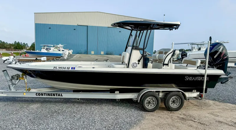 Slide: The Image of 2016 ShearWater 25LTZ boat on Continental trailer, parked near a blue warehouse. - 2