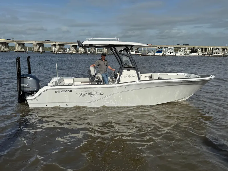 Slide: The Image of 2021 Sea Fox 248 Commander boat on water near a bridge, with a person at the helm. - 2