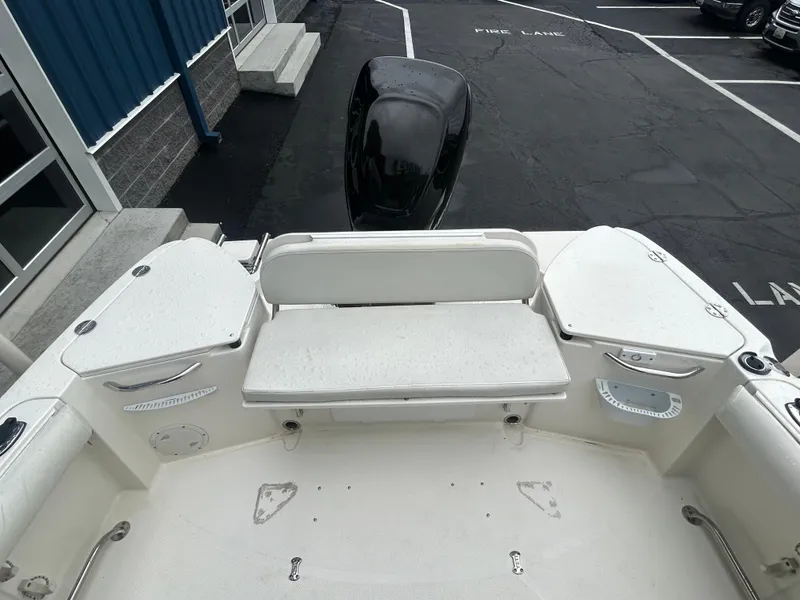 Slide: The Image of 2007 Trophy 2302 Walkaround boat interior with seating and motor, parked in a lot. - 4