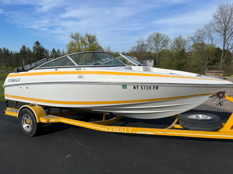 Slide: The Image of 2002 Cobalt 190 boat on yellow trailer, parked outdoors on a sunny day. - 0