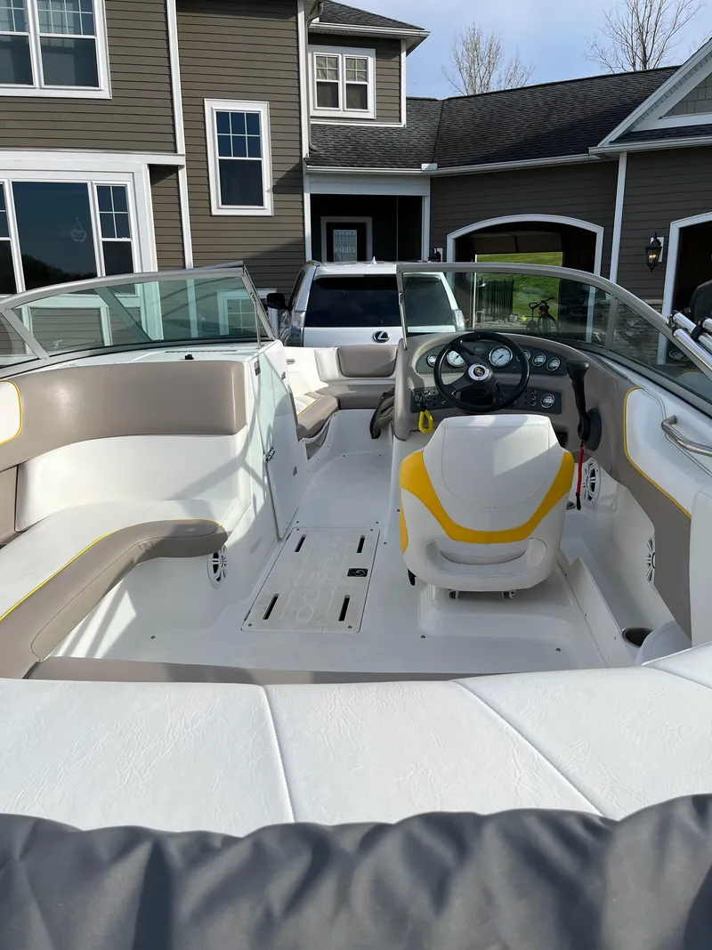 Slide: The Image of 2002 Cobalt 190 boat interior with steering wheel, seating, and dashboard, parked near a house. - 1