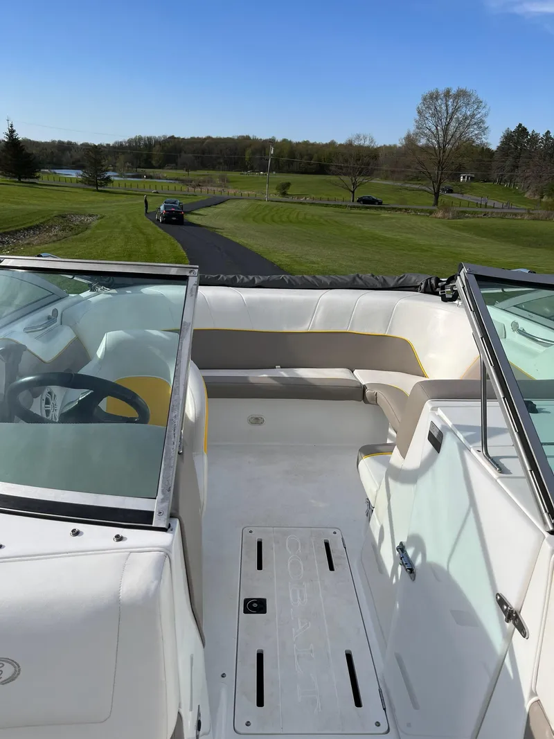 Slide: The Image of 2002 Cobalt 190 boat interior with white seating, parked on a grassy landscape. - 2