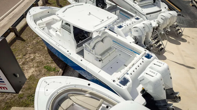 Slide: The Image of 2025 Everglades 315 CC boat with dual outboard engines, docked alongside similar vessels. - 15