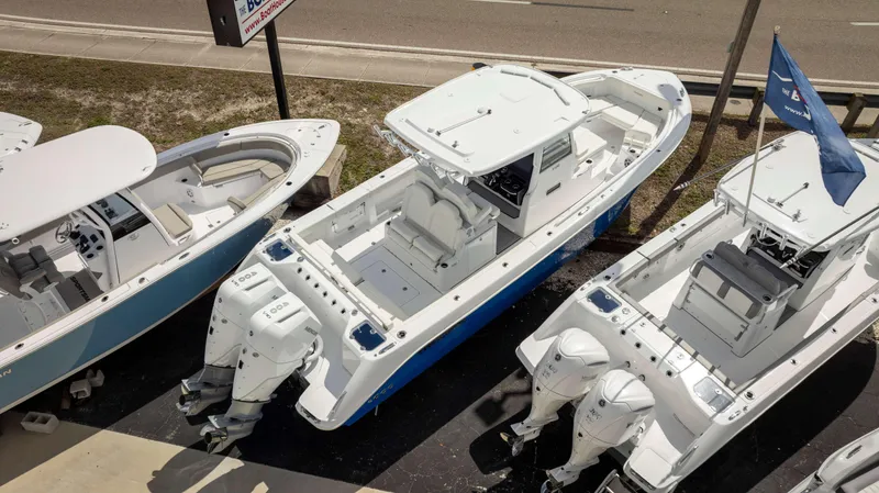 Slide: The Image of 2025 Everglades 315 CC boat with dual engines, docked alongside other boats. - 3