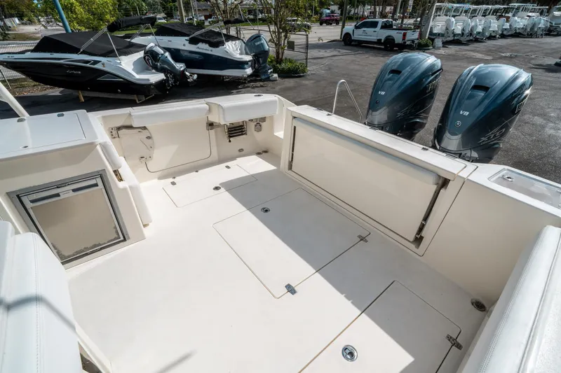 Slide: The Image of 2020 Cobia 330 DC boat deck with twin Yamaha V8 engines, parked near other boats. - 11