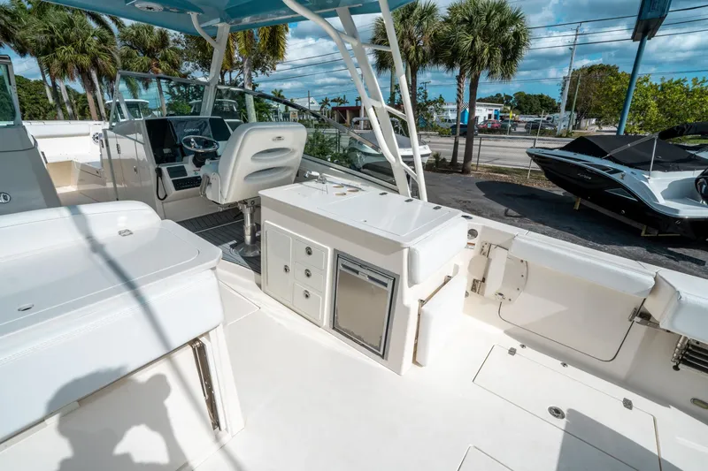 Slide: The Image of 2020 Cobia 330 DC boat interior with helm, seating, and storage, under a blue sky. - 19
