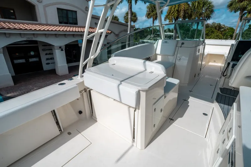 Slide: The Image of 2020 Cobia 330 DC boat interior with seating and storage, docked near a building. - 20