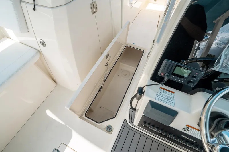 Slide: The Image of 2020 Cobia 330 DC boat interior with open storage compartment and control panel. - 33