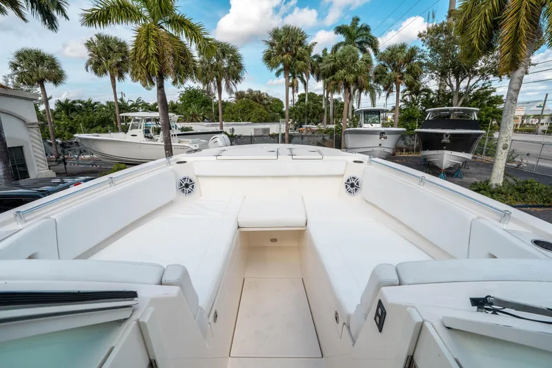 Slide: The Image of 2020 Cobia 330 DC boat interior with white seating and palm trees in the background. - 36