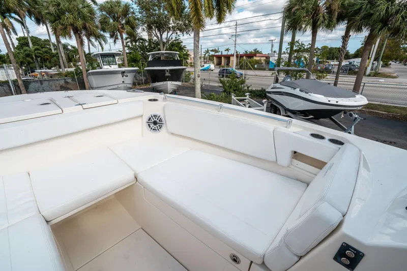 Slide: The Image of 2020 Cobia 330 DC boat interior with white seating, cup holders, and speaker, surrounded by palm trees. - 38