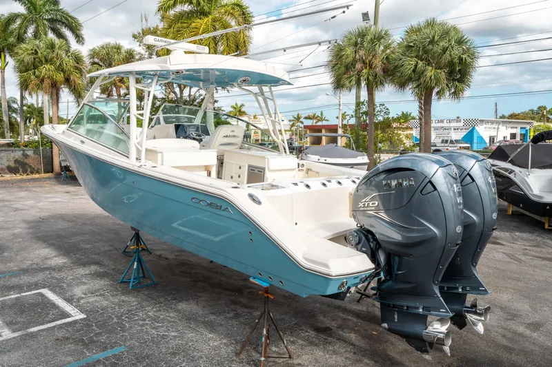 Slide: The Image of 2020 Cobia 330 DC boat with twin Yamaha engines, parked outdoors. - 4