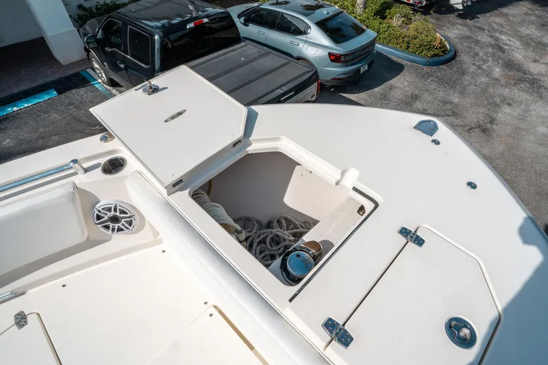 Slide: The Image of 2020 Cobia 330 DC boat with open storage compartment, parked near vehicles. - 43