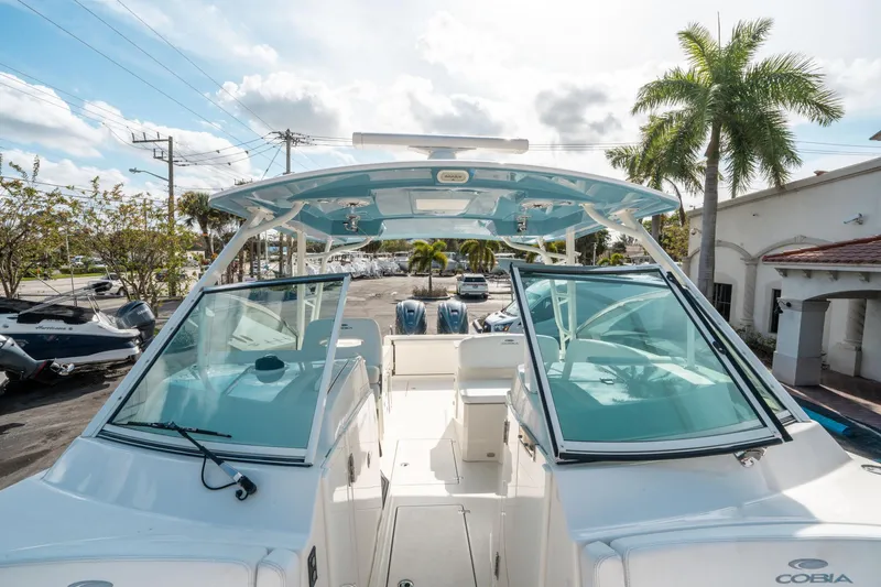 Slide: The Image of 2020 Cobia 330 DC boat with dual consoles, parked outdoors under a sunny sky. - 45