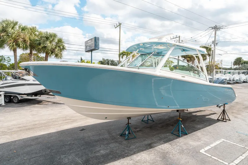 Slide: The Image of 2020 Cobia 330 DC boat on stands, displayed outdoors under a partly cloudy sky. - 6