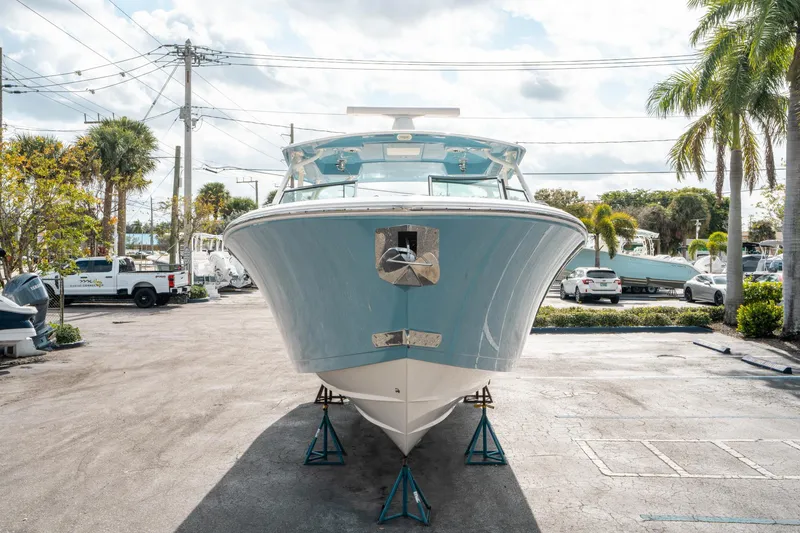 Slide: The Image of 2020 Cobia 330 DC boat on stands in a sunny marina setting. - 7