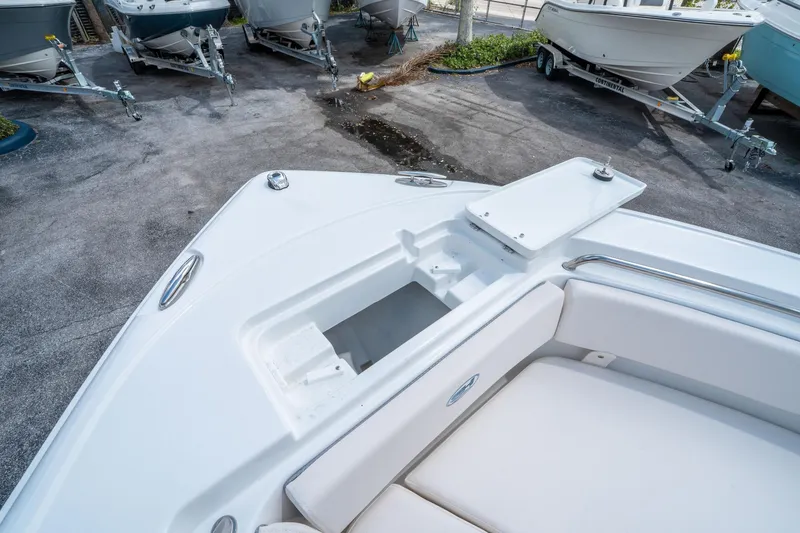 Slide: The Image of 2025 Sea Hunt Ultra 219 boat interior with storage compartment, surrounded by other boats on trailers. - 26