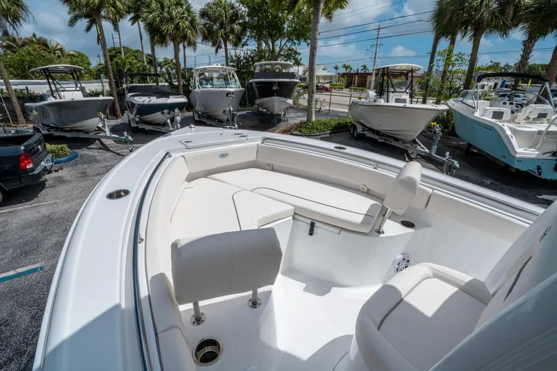 Slide: The Image of 2025 Sea Hunt Ultra 219 boat interior with seating, parked among other boats under palm trees. - 21