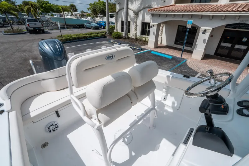 Slide: The Image of 2025 Sea Hunt Ultra 219 boat interior with helm and seating in a parking lot. - 18