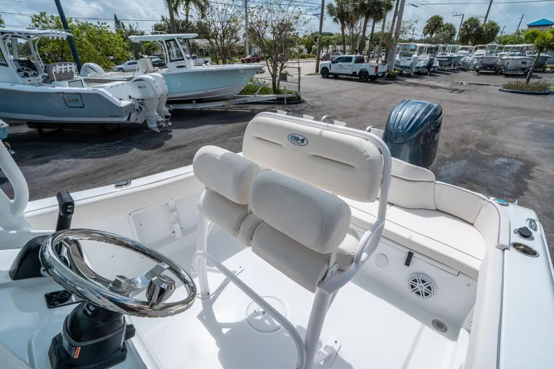 Slide: The Image of 2025 Sea Hunt Ultra 219 boat interior with steering wheel and seating, parked outdoors. - 17