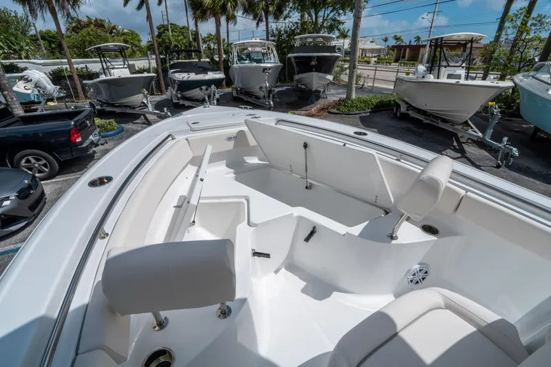 Slide: The Image of 2025 Sea Hunt Ultra 219 boat interior with seating, parked among other boats. - 24