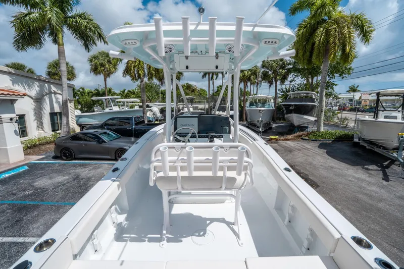 Slide: The Image of 2025 Sea Hunt Ultra 219 boat in a sunny marina with palm trees. - 9