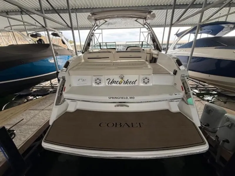 Slide: The Image of 2020 Cobalt R30 boat docked, rear view, featuring spacious deck and seating. - 4