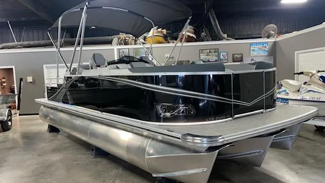 The Image of 2025 Tahoe LTZ 2385 RL pontoon boat in showroom, featuring sleek black design and modern amenities. - 1