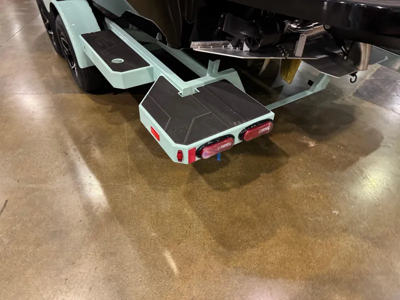 Slide: The Image of 2025 Moomba Max boat trailer with teal accents and dual taillights on display indoors. - 7