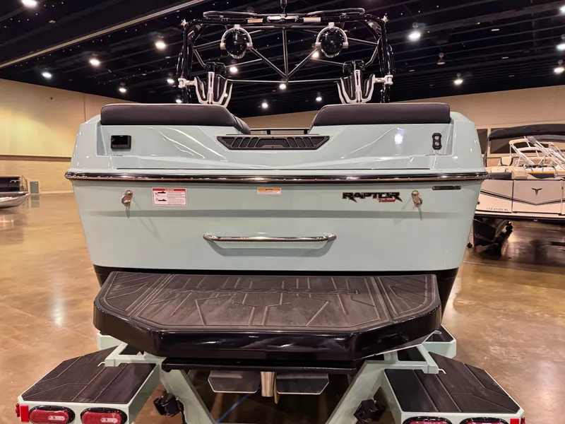 Slide: The Image of 2025 Moomba Max boat rear view in showroom, featuring Raptor engine branding. - 8