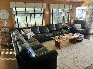 Slide: The Image of Luxurious Sumerset 90x18 houseboat interior with black leather sectional, wooden table, and large windows. - 25