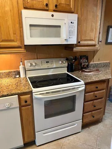 Slide: The Image of Kitchen with white stove, microwave, wooden cabinets, and granite countertops in a 2005 Sumerset 90x18. - 30