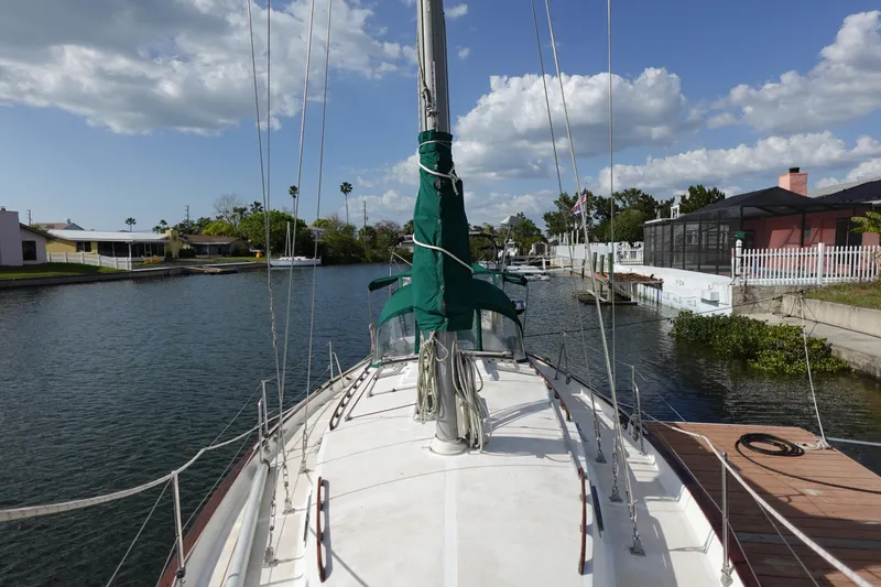 Slide: The Image of 1982 Morgan 383 sailboat docked in a peaceful canal, surrounded by residential homes. - 10