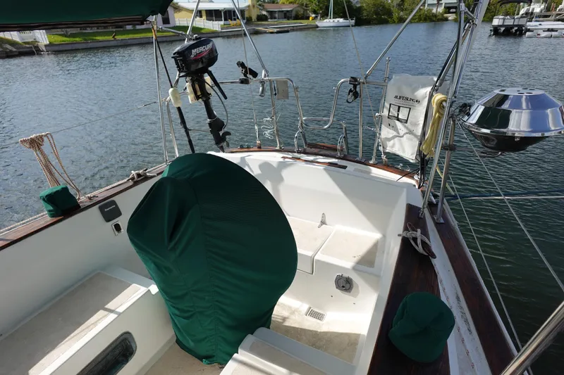 Slide: The Image of 1982 Morgan 383 sailboat cockpit with green covers, docked by a calm waterfront. - 13