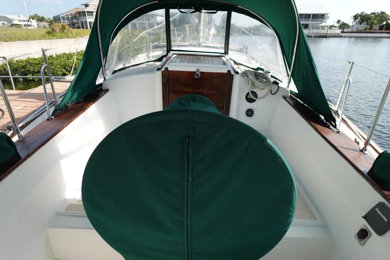 Slide: The Image of 1982 Morgan 383 sailboat cockpit with green canopy and seating, docked by the water. - 15
