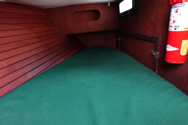 Slide: The Image of Cozy cabin interior of 1982 Morgan 383 sailboat with green bedding and wooden paneling. - 26