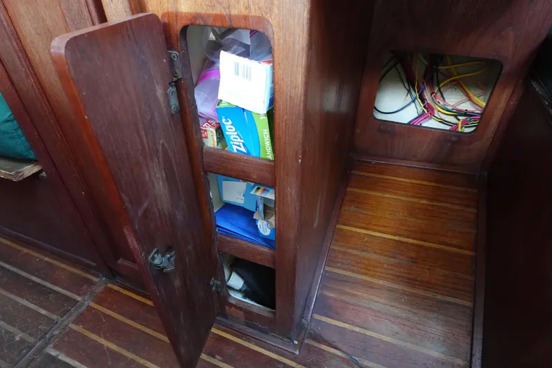 Slide: The Image of Wooden cabinet with open door, revealing storage shelves and wiring, inside a 1982 Morgan 383 boat. - 30