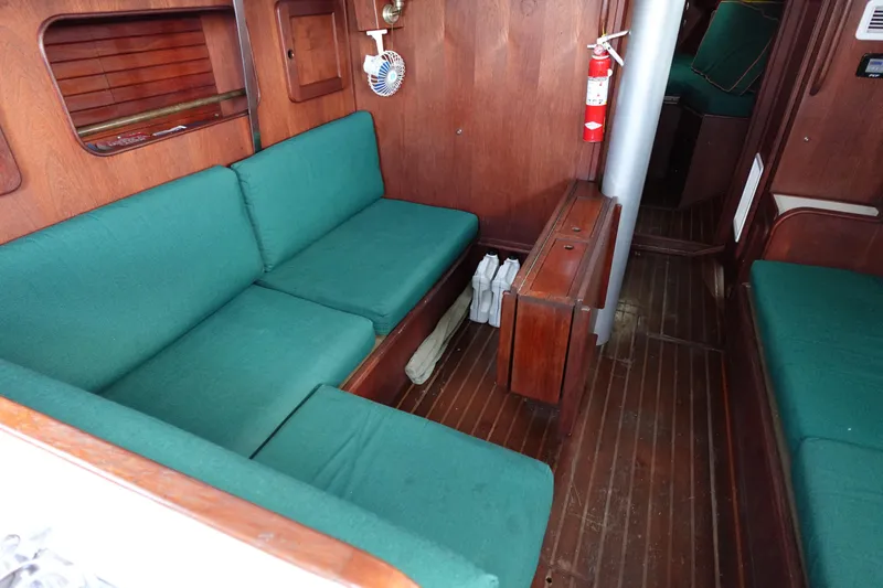 Slide: The Image of Interior of a 1982 Morgan 383 sailboat with green cushioned seating and wooden paneling. - 33