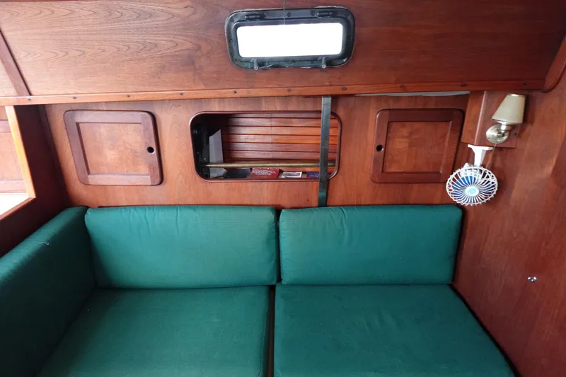 Slide: The Image of Interior of a 1982 Morgan 383 sailboat with green cushions and wooden paneling. - 34