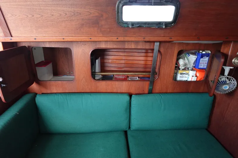 Slide: The Image of Interior of a 1982 Morgan 383 sailboat with green cushions and wooden cabinetry. - 35