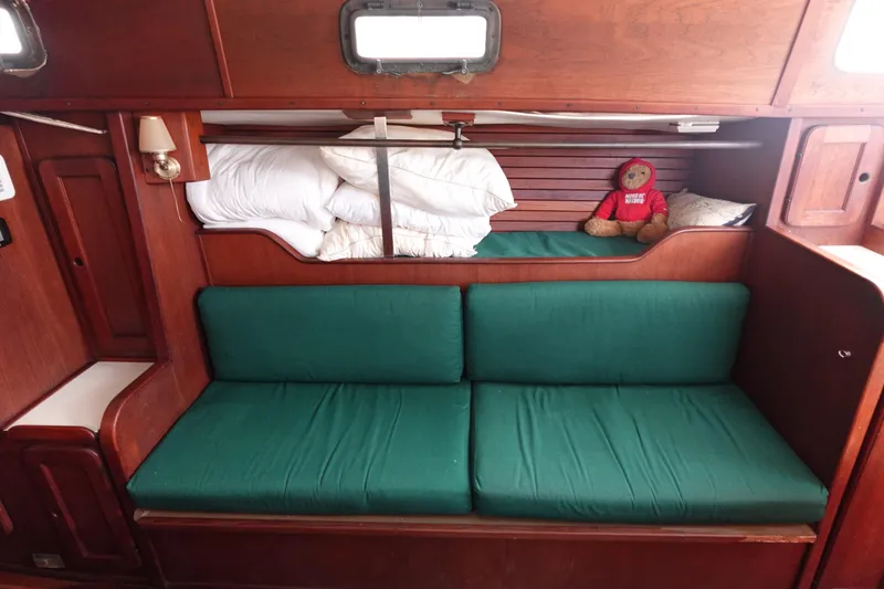 Slide: The Image of 1982 Morgan 383 sailboat interior with green cushions and wooden finish. - 36