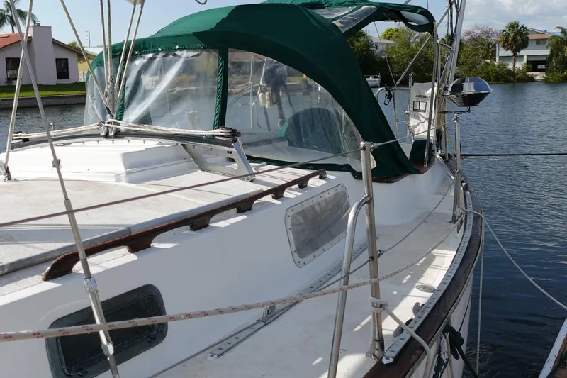 Slide: The Image of 1982 Morgan 383 sailboat with green canopy docked by a calm waterfront. - 5