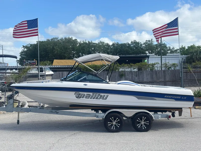 Slide: The Image of 2001 Malibu Response LX boat on trailer, parked with American flags in the background. - 0